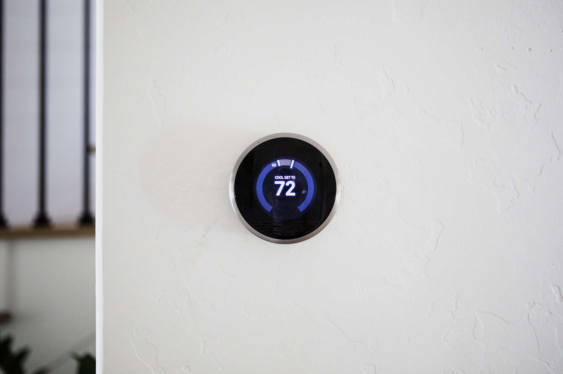 A modern, circular digital thermostat mounted on a white wall displays a temperature of 72 degrees Fahrenheit.