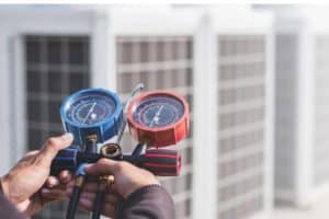 HVAC technician checking refrigerant levels while running AC with low refrigerant