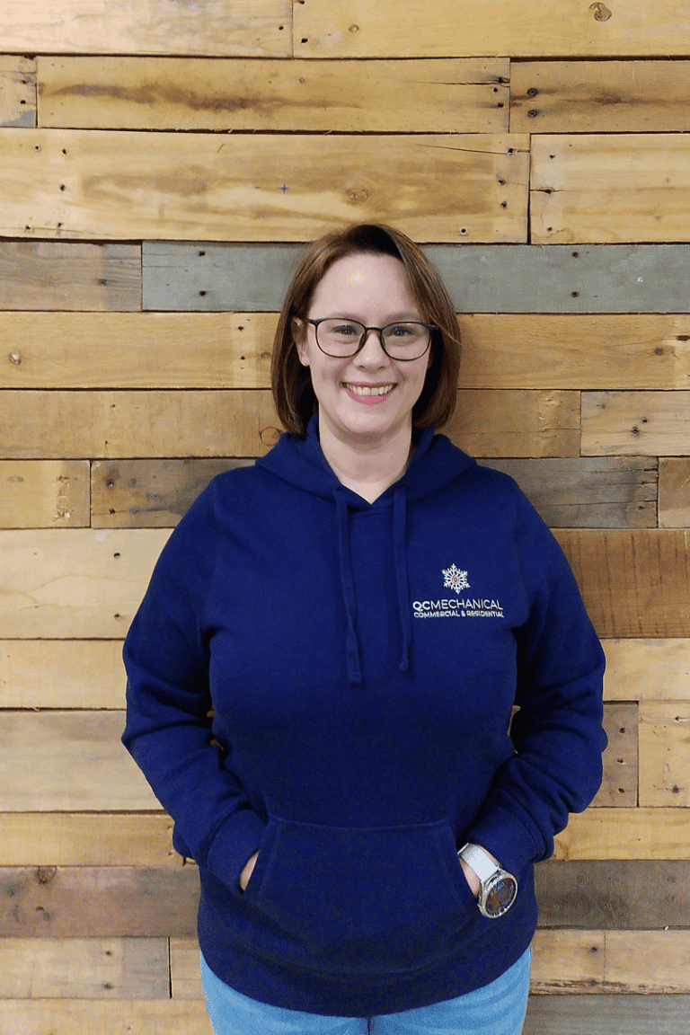 A woman with short brown hair and glasses, wearing a navy hoodie with
