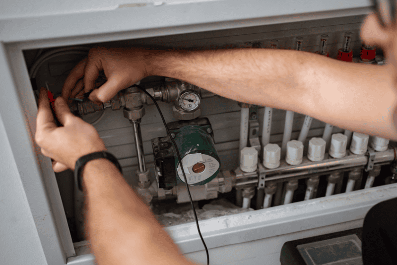 Technician checking connections inside a residential heating control panel