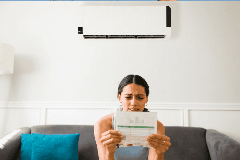 Woman looking at a high electricity bill asking why is my AC bill so high